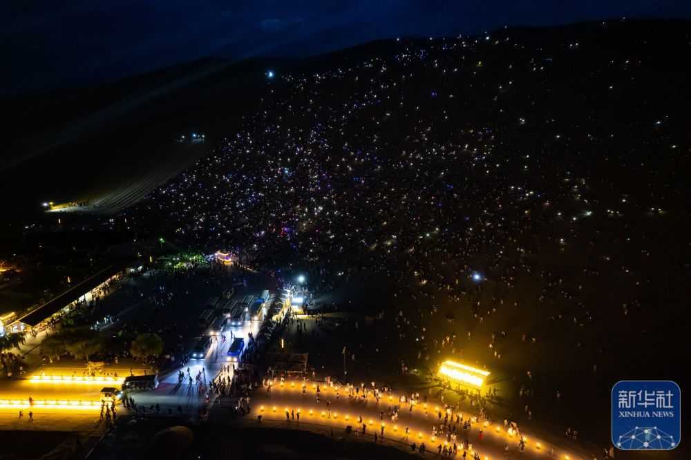 7月15日晚，游客在敦煌鸣沙山月牙泉景区参加万人星空演唱会（无人机照片）。