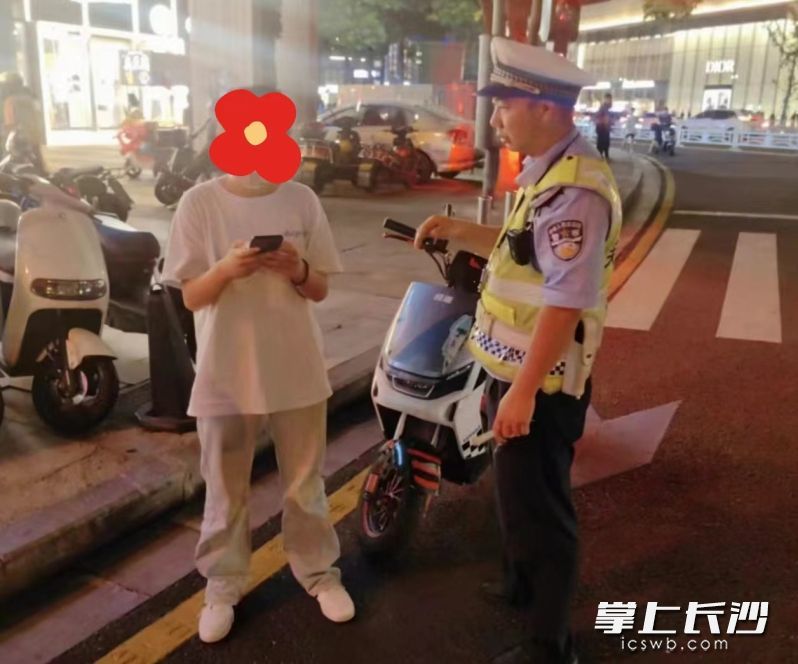 电动自行车险些与一辆正常行驶的小轿车发生碰撞，执勤民警连忙将其拦停。长沙晚报通讯员 屈省 供图