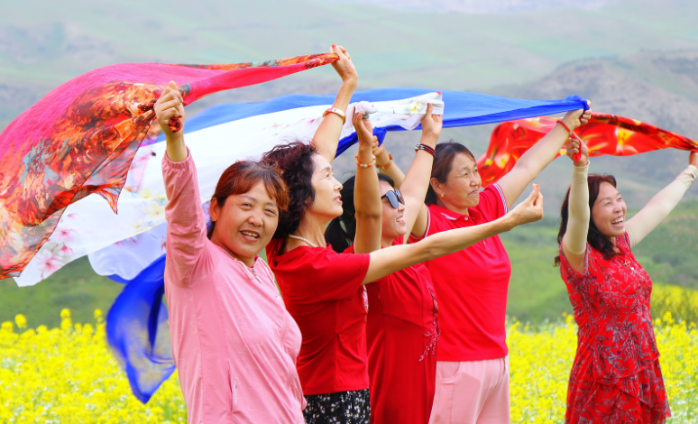 花海与远山相融，游客沉醉其间。