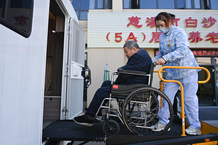 2023年11月19日，在浙江省慈溪市白沙路街道居家养老服务中心，81岁老人吴森泉（左）在助浴师的陪同下进入移动助浴车接受助浴服务。新华社记者 黄宗治 摄