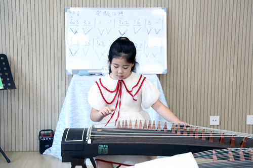 复兴大街小学暑期托管学生在古筝教室弹奏古筝