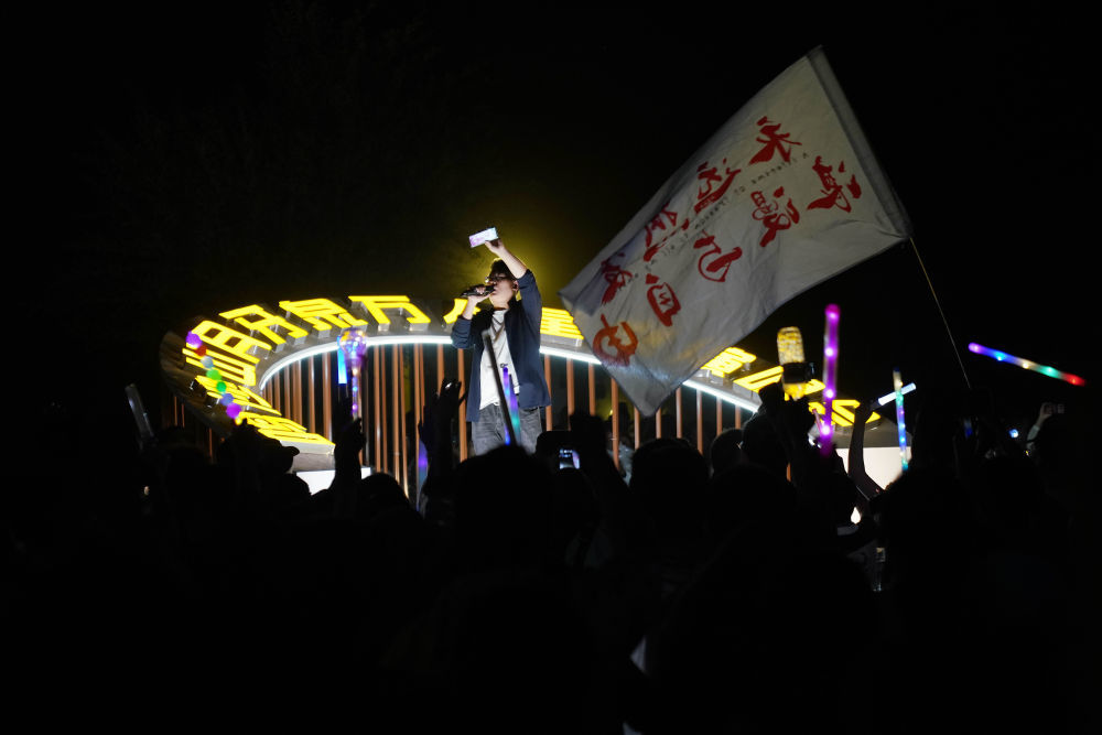 7月15日晚,敦煌鸣沙山月牙泉景区万人星空演唱会现场,主持人带领大家一起唱歌。新华社记者 马宁 摄