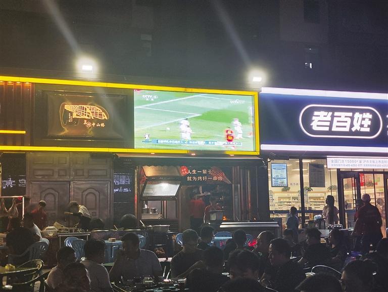 火车站附近一烤肉店摆出电视大屏吸引消费者