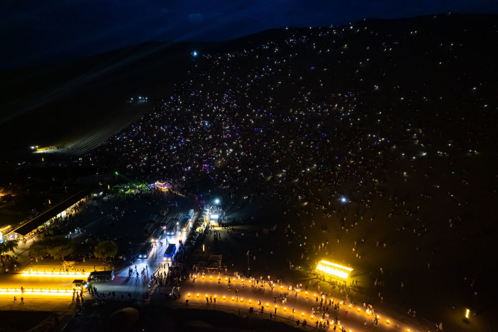 7月15日晚,游客在敦煌鸣沙山月牙泉景区参加万人星空演唱会(无人机照片)。新华社记者 郎兵兵 摄