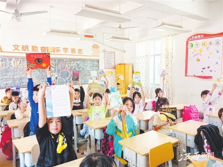 江西中行驻村帮扶工作队为窑塘小学修建图书角，孩子们高兴地展示着自己喜爱的图书。