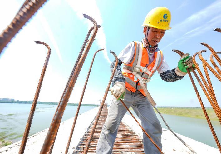 第三跑谈工程现场，竖立工东谈主们冒着盛暑责任