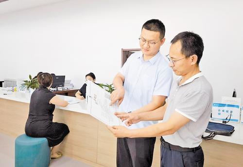 6月20日，在河北鹿泉经济开发区行政审批局，经过环评和排污许可“两证合一”审批，一家企业的工作人员（右）顺利领到排污许可证。本报记者 董昌摄