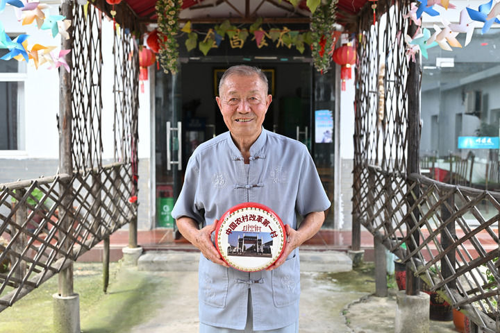 2024年7月25日，安徽凤阳小岗村“大包干”带头人严金昌在自家开办的农家乐里展示小岗村旅游纪念品凤阳花鼓。新华社记者　李鑫　摄