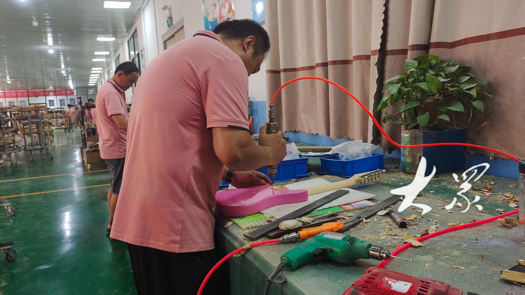 鄌郚镇昌韵达乐器厂里，一位工人正在使用工具作业。都亚男摄