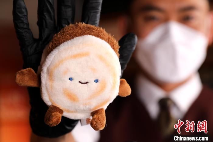 8月5日，陕西西安，工作人员展示“绒馍馍”。近日，西安文创产品“绒馍馍”走红网络，这款玩偶以肉夹馍为原型，用两块软绵绵的“馍”，巧妙地夹着一块柔软填充物模拟的“肉”，颇具创意。工作人员介绍，“绒馍馍”推出半个多月，已售出上万个。中新社记者 张远 摄