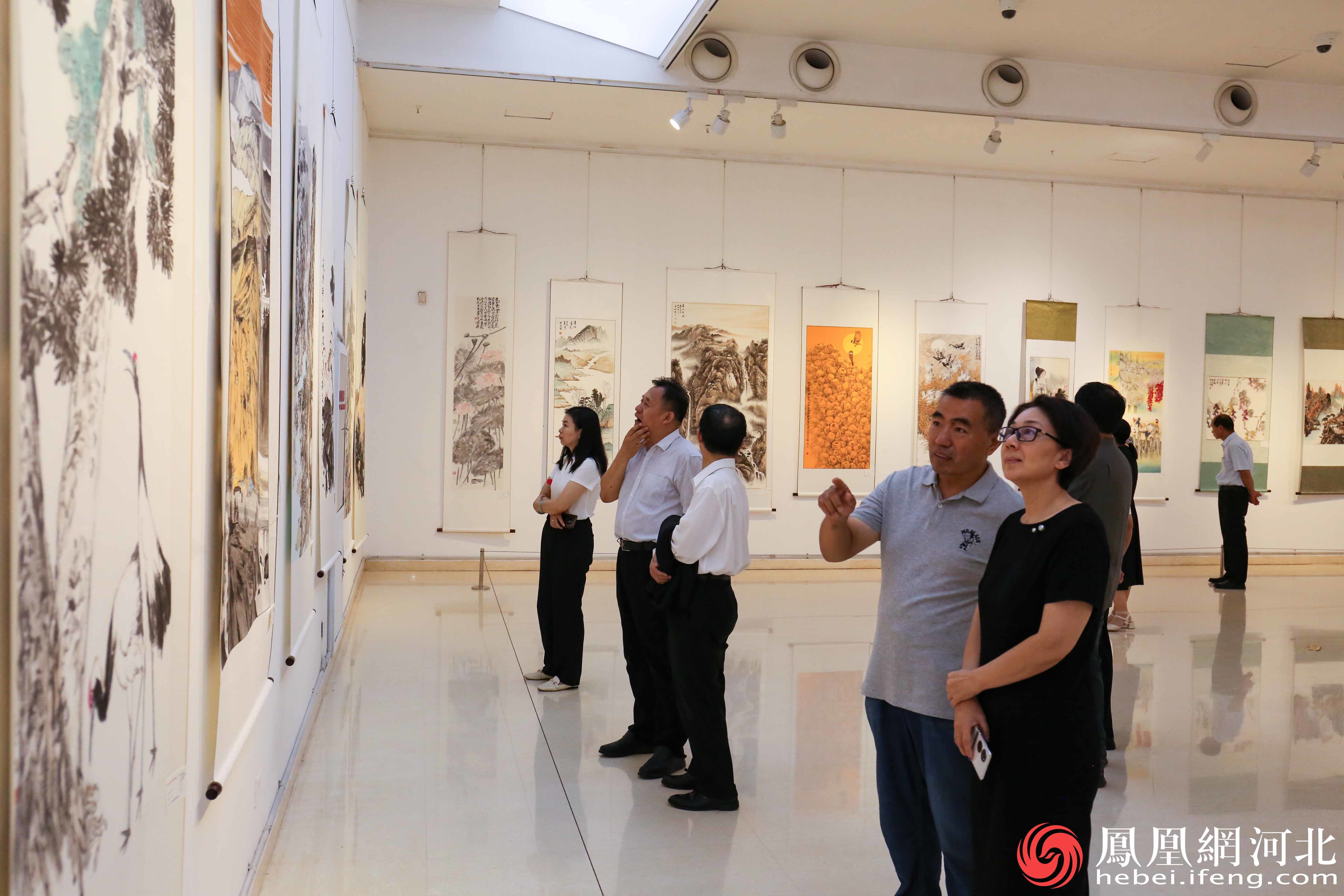 展出现场参观者们仔细参观欣赏每一幅书画摄影作品。