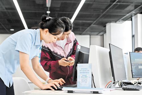 8月16日，雄安新区政务服务中心的大厅桌上摆放着“数字政务门牌”，工作人员（左）正在为前来办理业务的市民进行操作演示。 本报记者 郝金钰摄