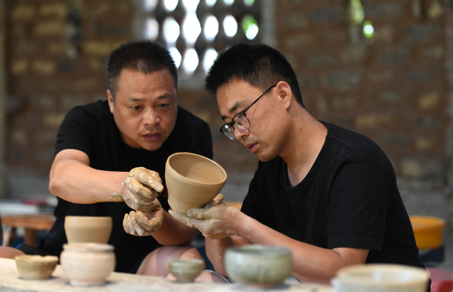 甘泰之（右）和陶瓷艺术老师交流陶瓷制作技艺。周亮/摄