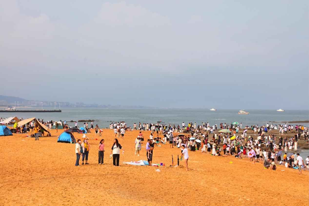 灯塔景区的海滩上，日出之后满是纳凉的游客。张守本 摄