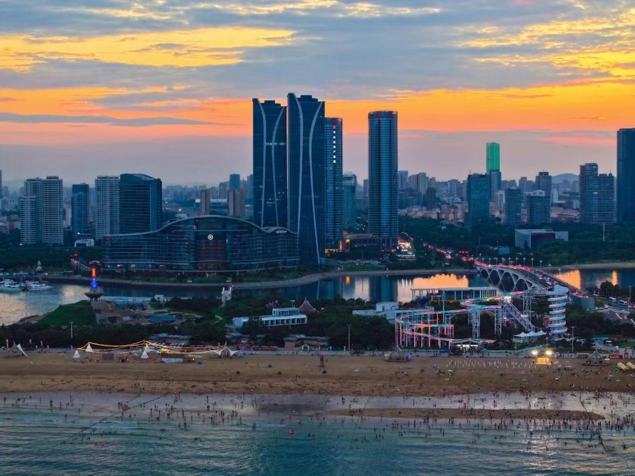 朝霞穿透云层，城市还未苏醒，海滩就已经热闹起来。宋年升 摄