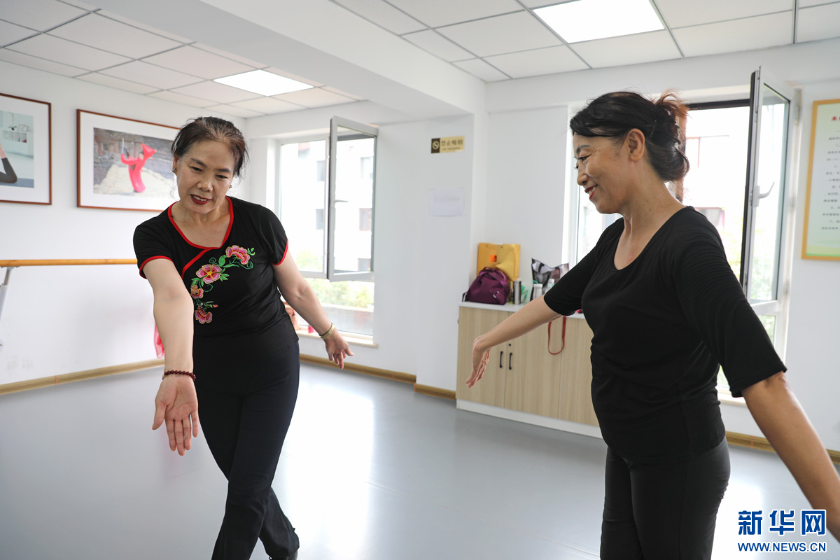 8月21日，丽水社区舞蹈队的指导老师刘玉华（左）和队长杨玉琴（右）在交流舞蹈动作。新华网 魏会博 摄