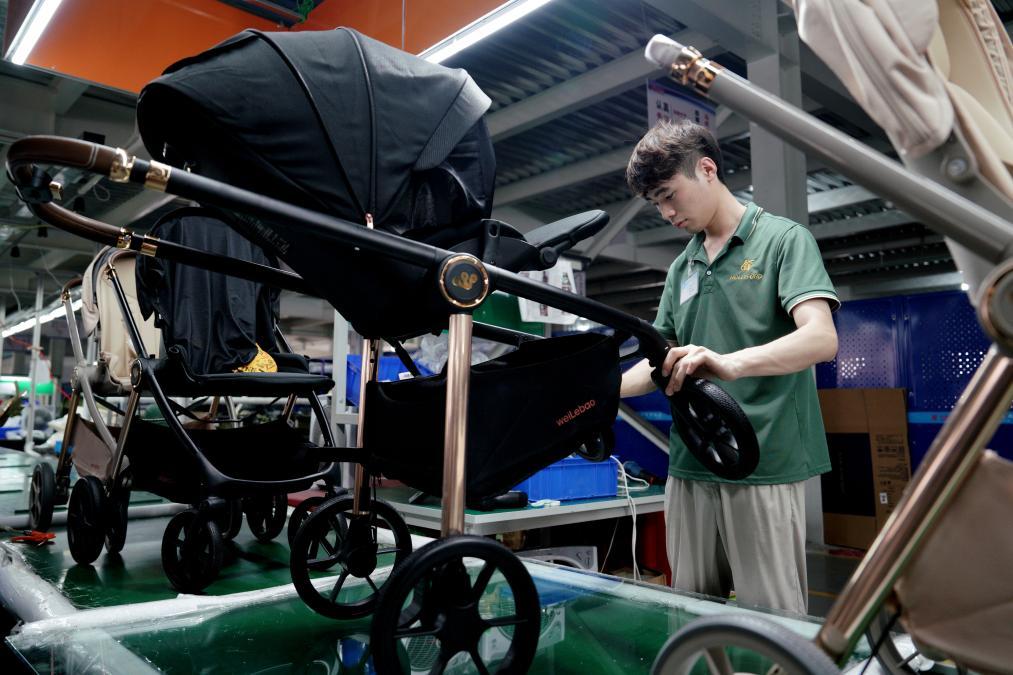 8月19日,河北省平乡县一家童车生产企业的员工在车间内组装儿童推车。