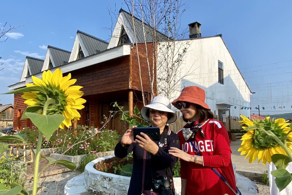 在黑龙江省大兴安岭地区漠河市北极镇北红村，游客在民宿前拍照。新华社记者 杨思琪 摄