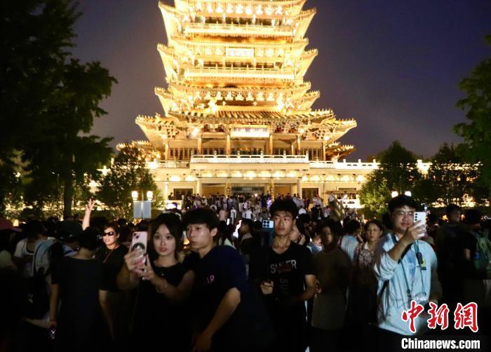 8月25日，山东济南，位于大明湖畔的超然楼亮灯引民众观看。图为民众在超然楼前合影留念。中新社记者 李明芮 摄