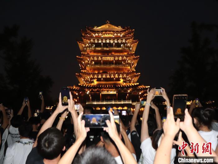8月25日，山东济南，位于大明湖畔的超然楼亮灯引民众观看，并拍照留念。中新社记者 李明芮 摄