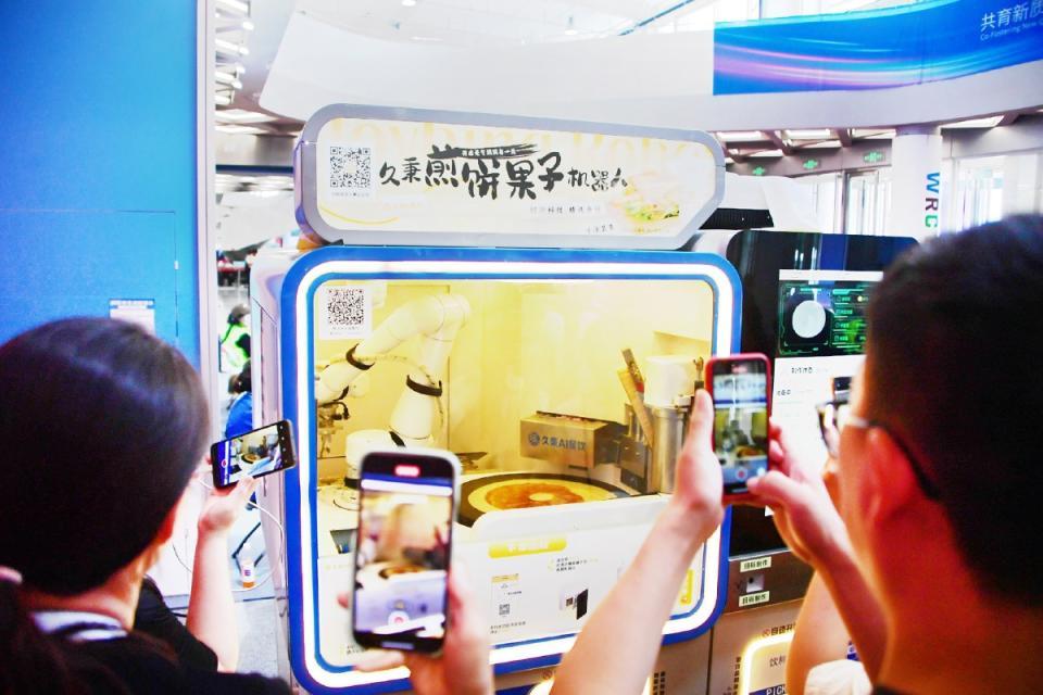 参观者争相体验煎饼机器人。记者 常鸣/摄