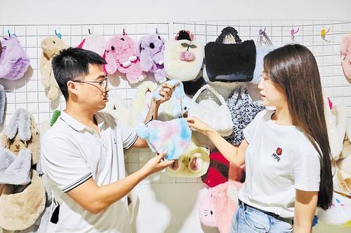 8月14日，枣强县大营镇石佛头村永汇毛皮有限公司老板张乐（左）向客户介绍他们的皮草饰品。 本报记者 焦 磊摄