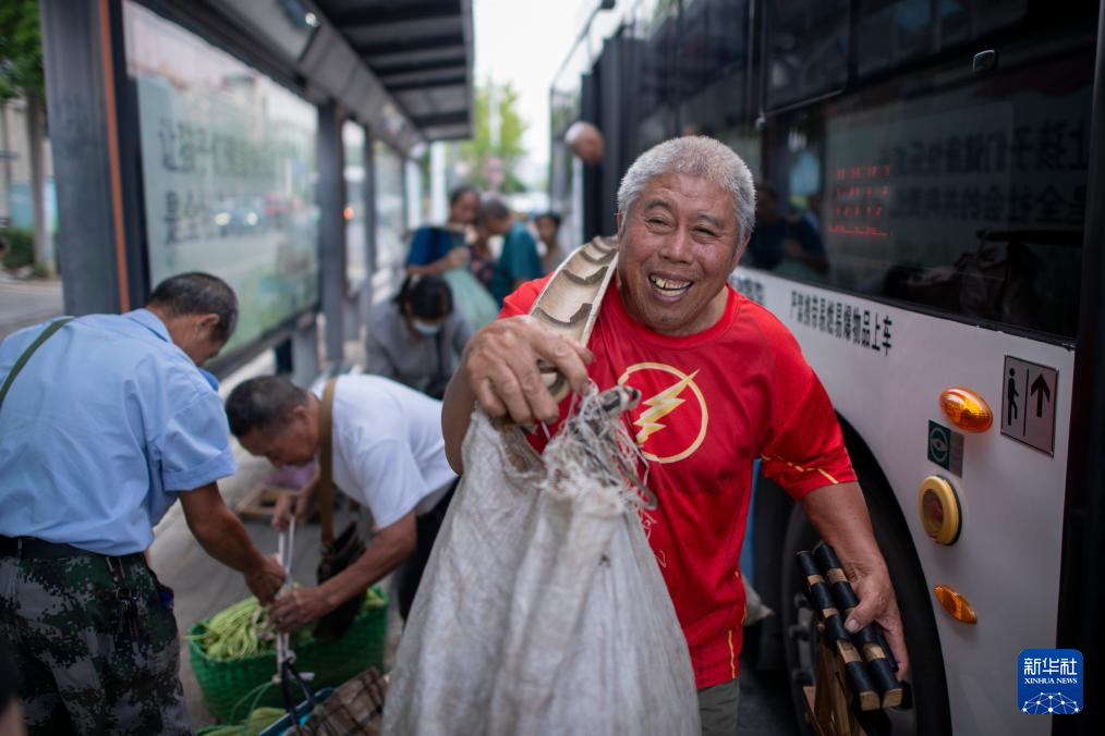 J202路公交车到达北华街站，涂继兴前往附近的菜市场卖菜。新华社记者伍志尊 摄