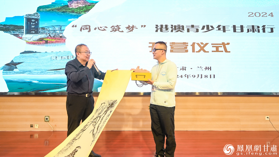 甘肃省政协住澳门委员、澳门甘肃联谊会副会长周胜（右）与兰州天庆实验中学校长齐景宏互赠礼物