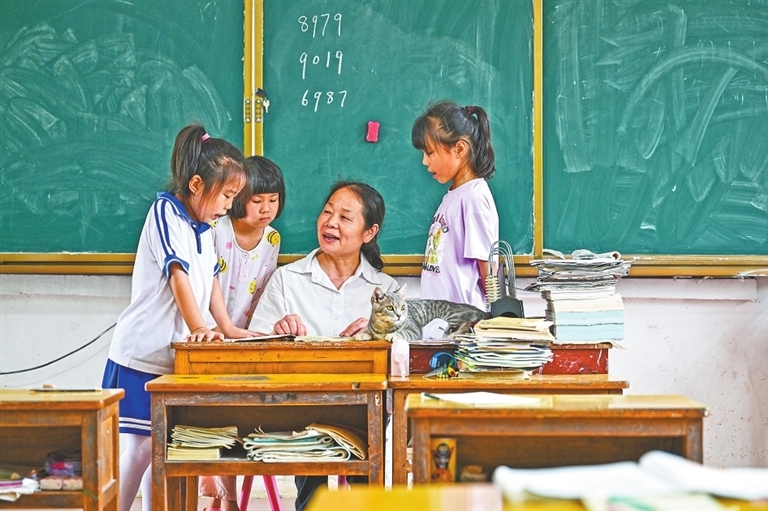 6月18日,在上高县蒙山镇小布小学,教师黎小玲正在给二年级的黎雨萱(右一)等全部3个孩子辅导作业。