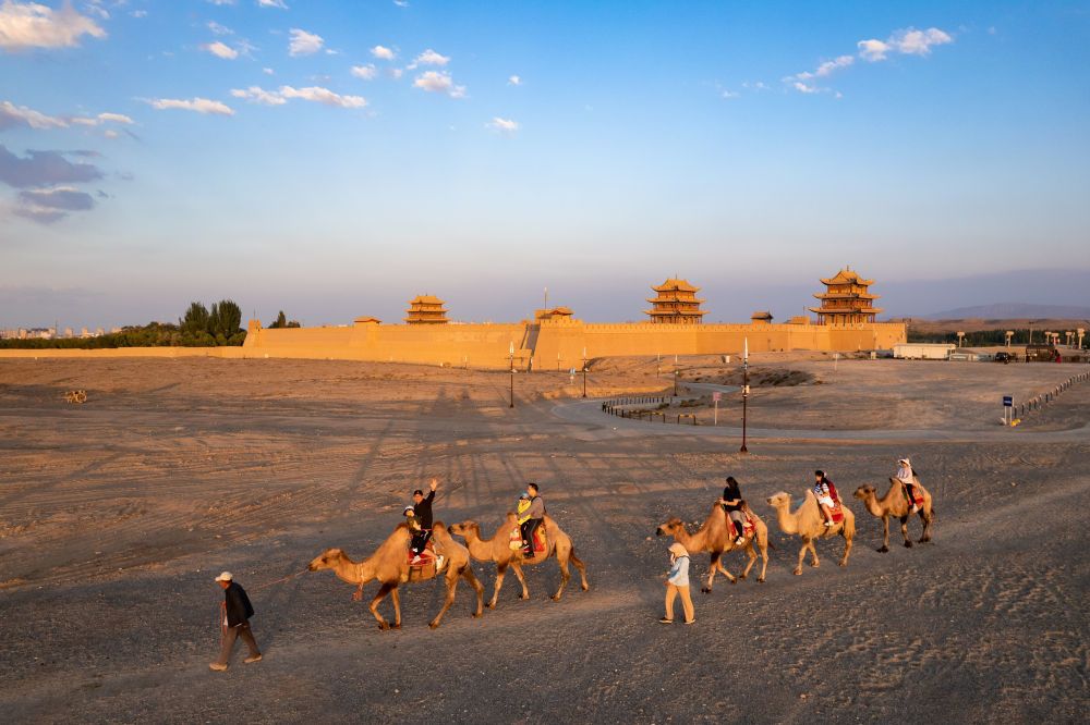 7月15日，游客在嘉峪关关城旁骑骆驼游览（无人机照片）。新华社记者　郎兵兵　摄