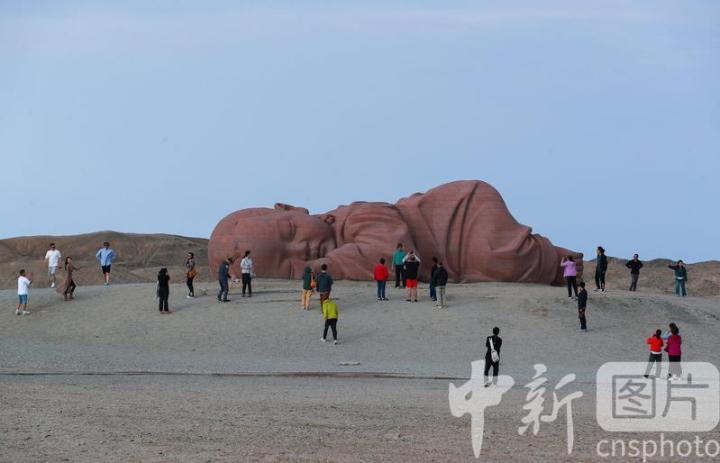 2024年9月19日，位于甘肃省酒泉市瓜州县城南20公里的戈壁国际雕塑艺术长廊，游客在雕塑艺术作品《大地之子》前打卡拍照。中新社发　陈坤　摄