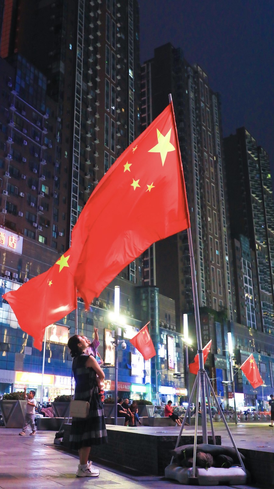 郑州万象城广场上，一位市民抱着孩子在仰望国旗。