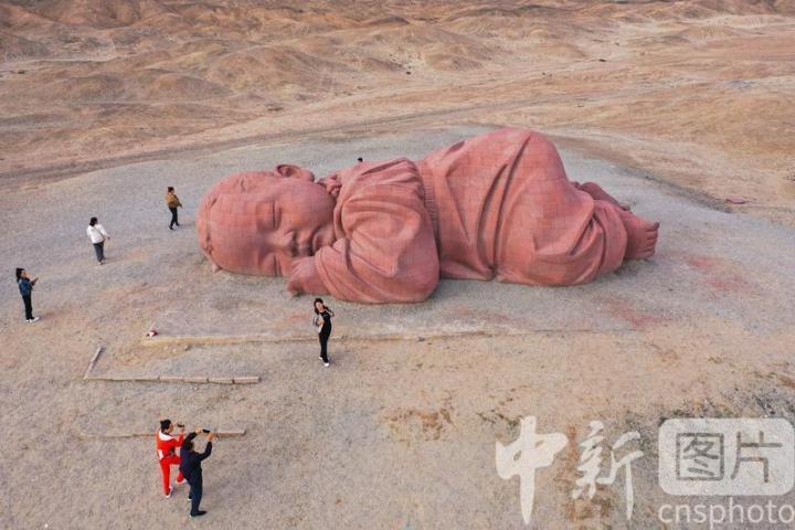 2024年9月19日，位于甘肃省酒泉市瓜州县城南20公里的戈壁国际雕塑艺术长廊，游客在雕塑艺术作品《大地之子》前打卡拍照。中新社发　陈坤　摄