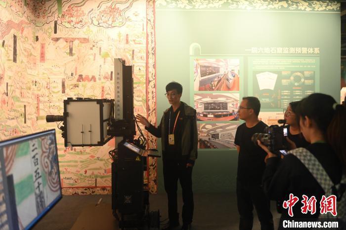9月21日，在甘肃省敦煌市第七届丝绸之路(敦煌)国际文化博览会展馆内，游客参观敦煌研究院“典范”“高地” 建设成果展中的第四代壁画高保真自动拍摄装置。中新社记者　李亚龙　摄