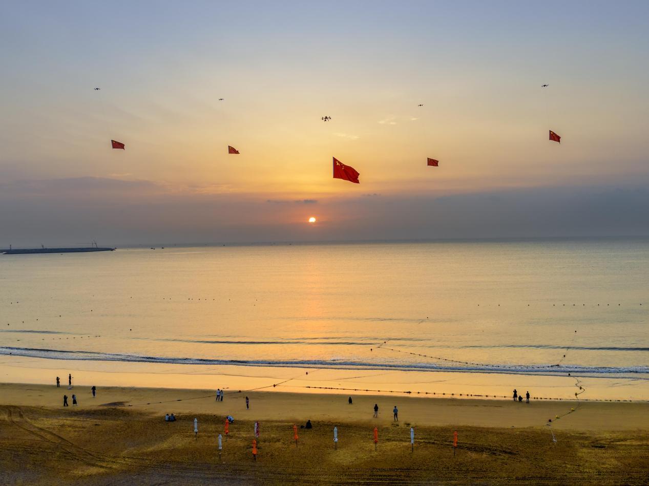 9月27日，万平口景区，鲜艳的五星红旗通过无人机舒展在浩瀚海洋上空。郑玉竹 摄