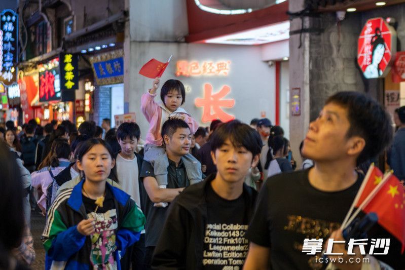 国庆期间，不少游客随身携带国旗出游。