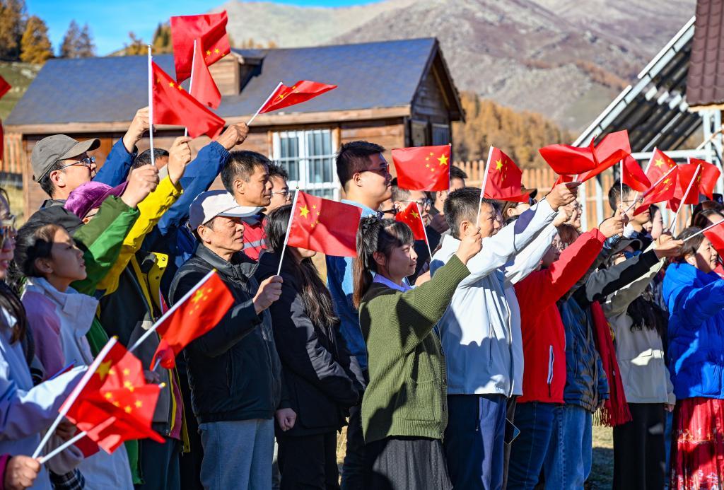 10月1日，在新疆阿勒泰边境管理支队乌希里克边境警务站，游客参加升国旗仪式。新华社记者 陈朔 摄