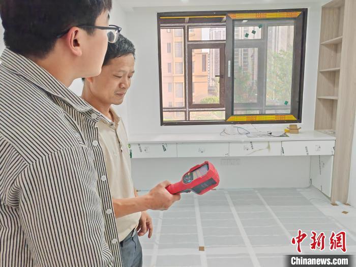 图为施工人员正在用热红外线地暖测漏仪检查地暖铺设情况。潘雪明 摄