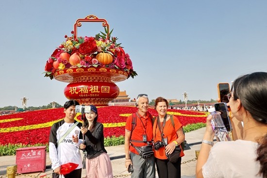 国庆节期间，北京天安门，国庆主题花坛“祝福祖国”巨型花篮吸引中外游客“打卡”。视觉中国供图