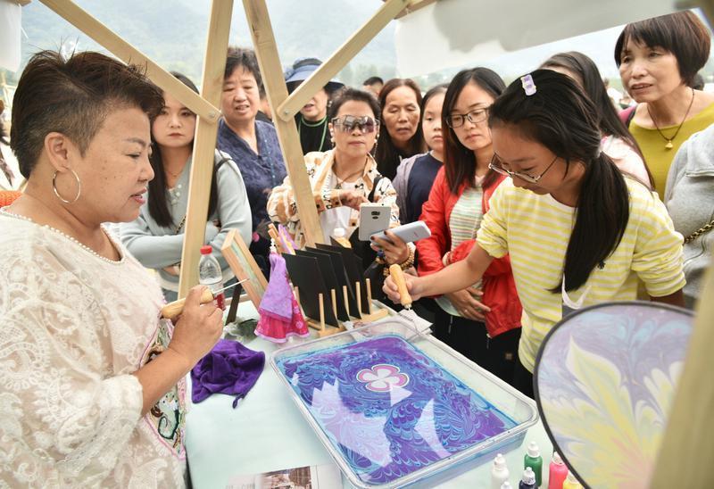 市民游客在蔡家坡村体验非遗漂漆扇制作。