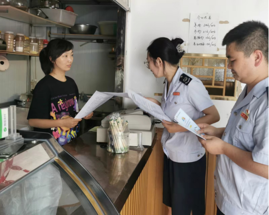 税务干部为个体经营者宣传税费优惠政策