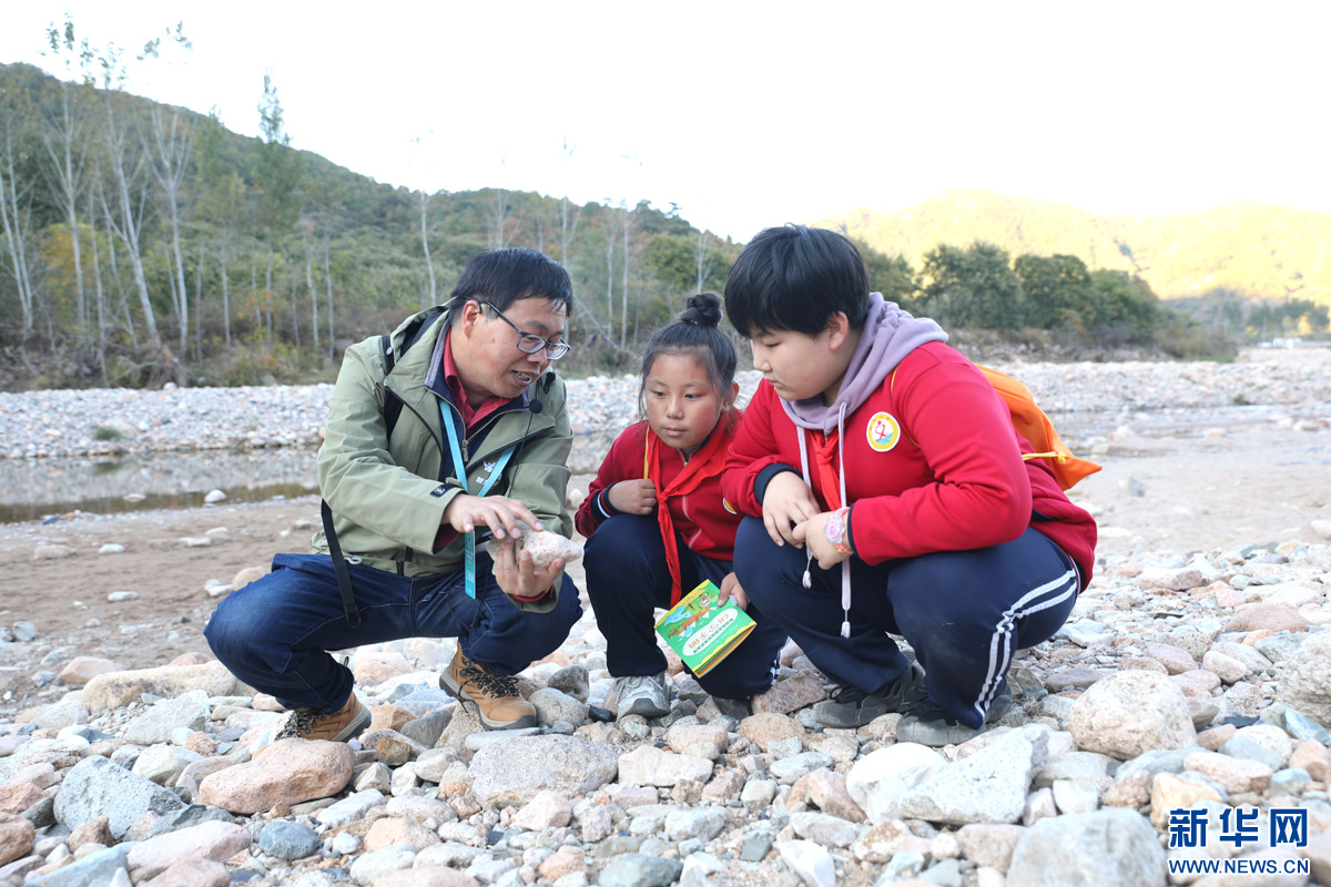在活动的“河滩寻宝”环节，学生们到大石河的河滩搜寻不同类型的石头，并请专家进行讲解。新华网 魏会博 摄