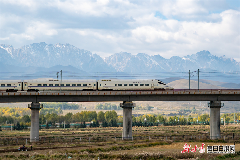 10月12日，在兰张高铁兰武段，列车从武威天祝县马牙雪山下驶过。