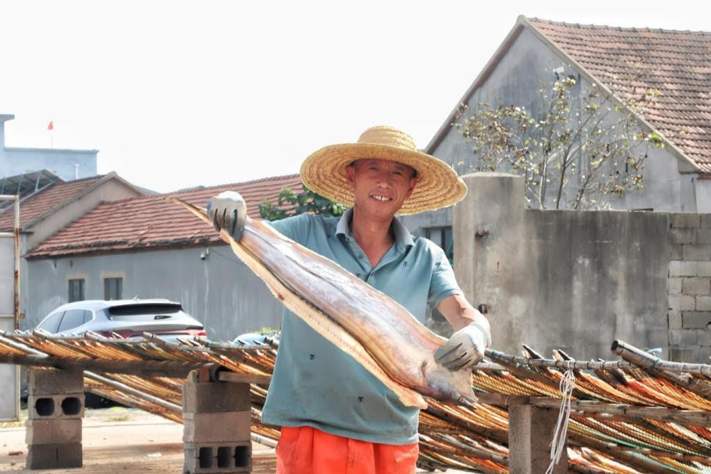 10月15日,岚山区安东卫街道,渔民展示晾晒好的鱼干,脸上洋溢着丰收的喜悦。叶雯 摄