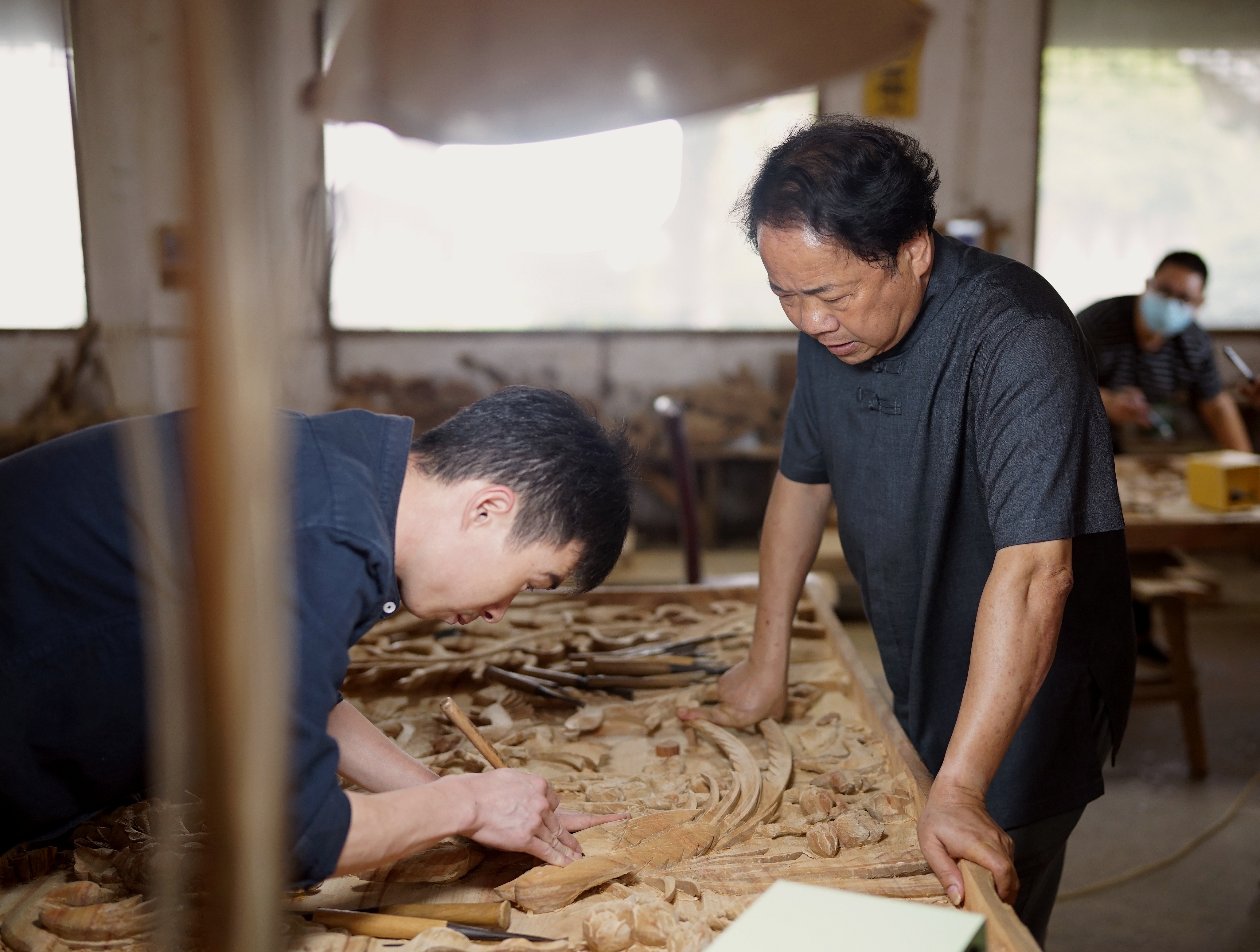 ▲国家级非遗婺源三雕代表性传承人俞有桂（右）在传艺。摄影｜江西日报全媒体记者陈米欧