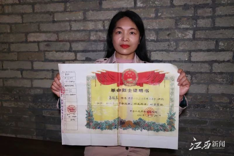 ▲易克美与大爷爷易冠美革命烈士证明书的合影。
