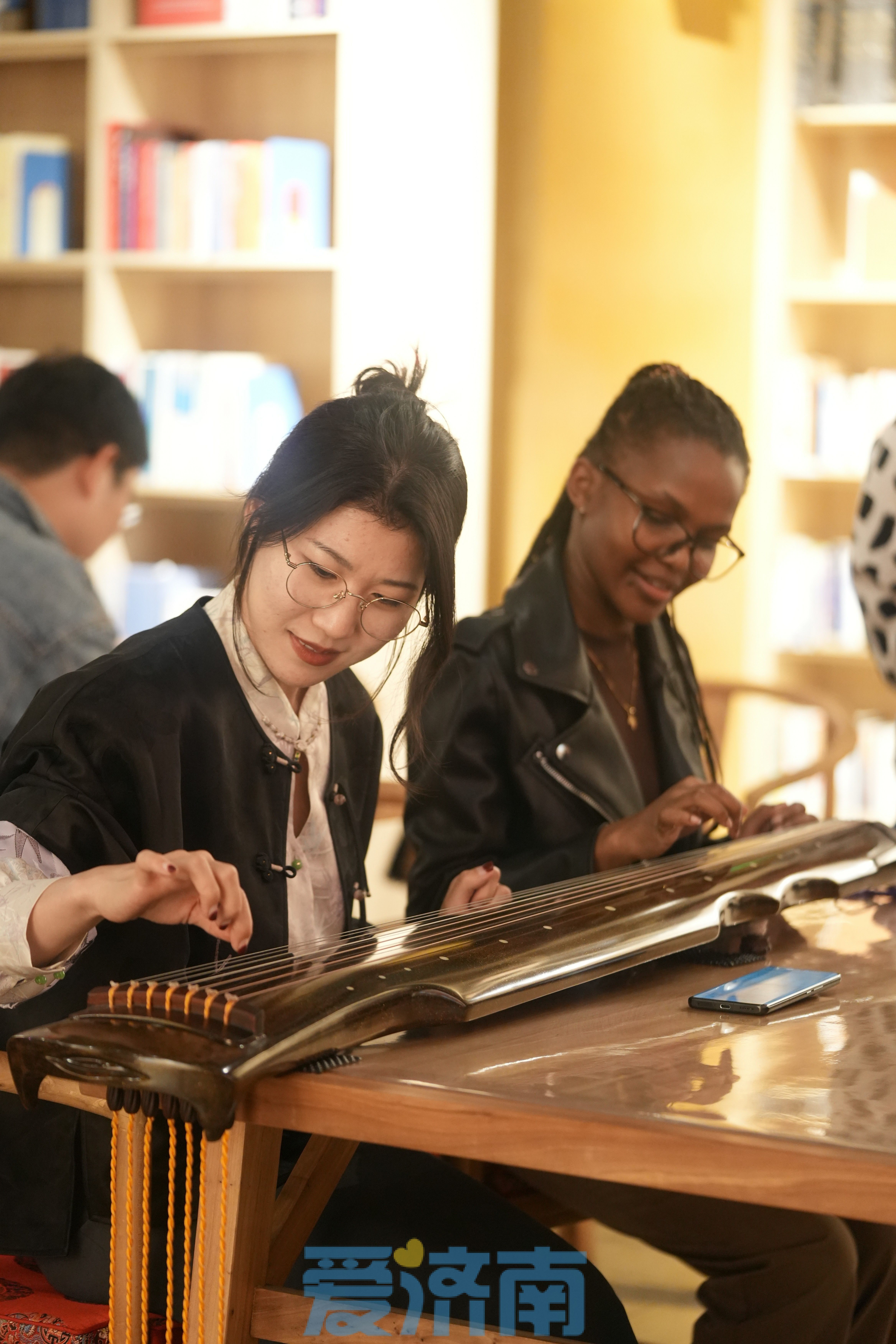 Go up外语俱乐部中国会员马丽（左）和山东师范大学肯尼亚留学生暮云（右）学习古琴