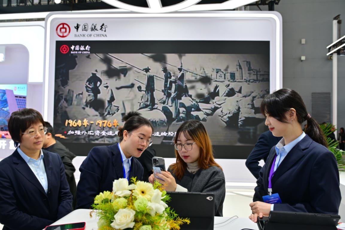 图为中国银行工作人员为观众讲解数币优惠活动 翁志刚/摄