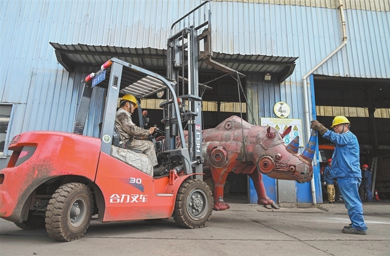 在物流储运中心汽车运输站，修理工在吊装钢铁机器人。