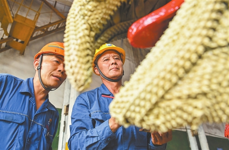 在物流储运中心汽车运输站火车维修厂房，副站长龚承勇（左）和钳工党卫平正认真打磨钢铁机器人作品。